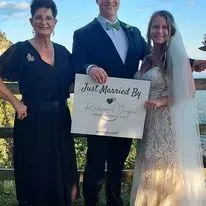 Newlyweds and Reverend Jayne holding a Just Married sign