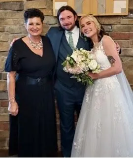 Reverend Jayne with a bride and groom holding a bouquet