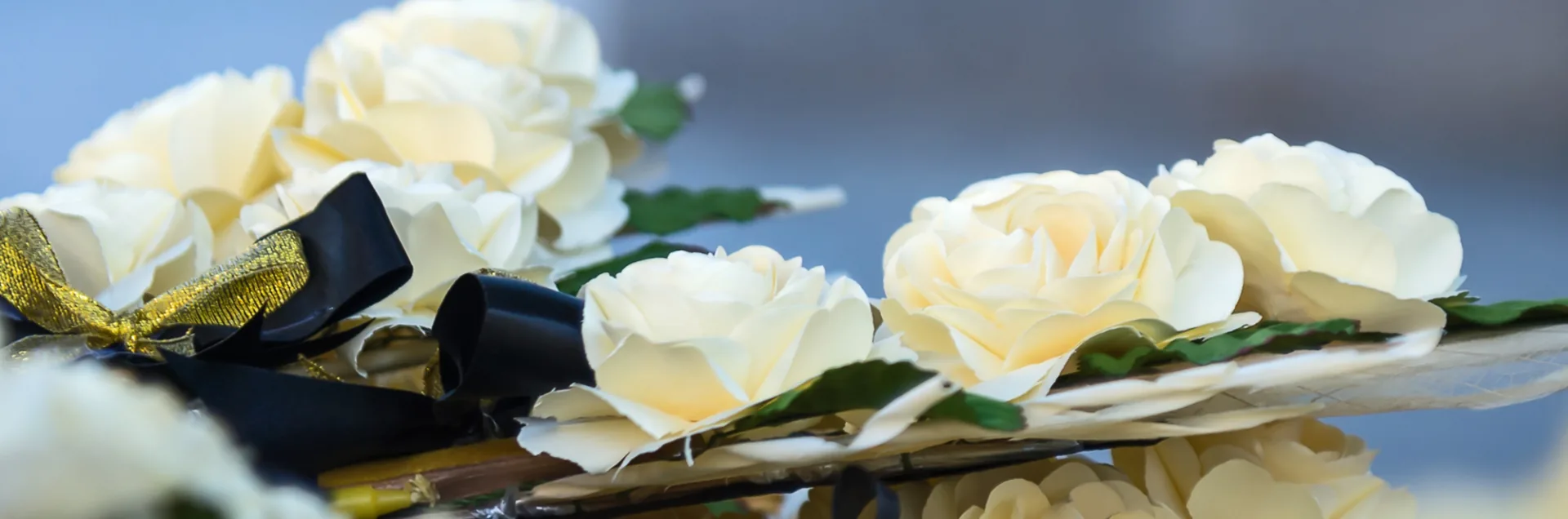 White roses with dark ribbon floating on water